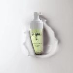 Fiole de nettoyant moussant sur un fond lisse et liquide, mettant en valeur l'élégance des soins de la peau.