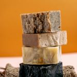 Une pile de savons naturels faits main sur un tapis texturé avec un fond chaud.