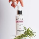 Une main tendue vers un produit capillaire infusé au romarin avec un emballage moderne.