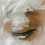 A serene close-up of a closed eye with white clay face mask applied for skincare. Fermeture sereine d'un œil avec un masque facial à l'argile blanche appliqué pour les soins de la peau.