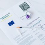 Certificat COVID numérique de l'UE avec des flacons de vaccin et une seringue sur fond blanc