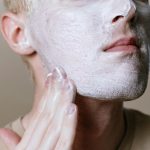 Close-up d'un homme appliquant un nettoyant pour le visage, mettant l'accent sur les soins de la peau et l'hygiène.