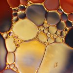 Gros plan sur l'interaction colorée de l'huile et de l'eau créant un motif abstrait vibrant.