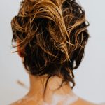 Gros plan de cheveux blonds mouillés vus de dos, capturant un moment sous la douche et de bien-être.