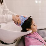 Une femme profite d'un shampoing relaxant dans un salon de coiffure moderne, mettant en avant les soins personnels et le bien-être.