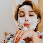 Close-up d'une femme appliquant un nettoyant moussant pour le visage, s'adonnant aux soins personnels en intérieur.