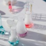 High-angle view de flacons de laboratoire colorés avec des liquides en évaporation sur une surface blanche
