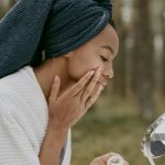 Woman profitant d'une routine de soins de la peau dans un cadre forestier, appliquant de la crème avec une concentration sereine