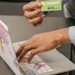 Person utilisant un ordinateur portable pour des achats en ligne avec une carte de crédit, axé sur le paiement numérique.