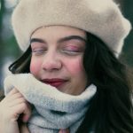 Une vue rapprochée d'une femme en vêtements d'hiver chauds, les yeux fermés, profitant d'une journée enneigée.