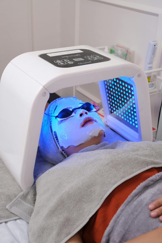 A facial skincare treatment featuring blue light therapy with a relaxing mask. Un traitement de soin du visage avec thérapie par lumière bleue et un masque relaxant.