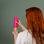 Adult woman with wet red hair applying conditioner. Hair care routine. Femme adulte aux cheveux rouges mouillés appliquant un après-shampoing. Routine de soins capillaires.