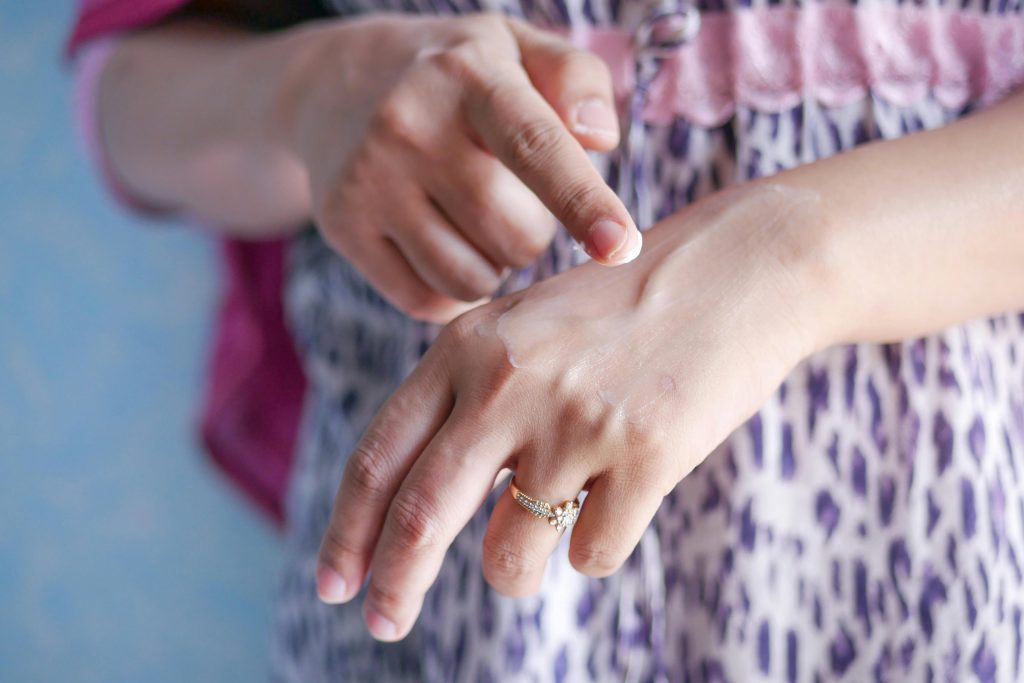 A woman applies skincare cream on her hand, highlighting moisturizing routine. Une femme applique une crème de soin sur sa main, mettant en évidence la routine hydratante.