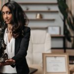 A female lawyer presenting a Lady Justice statue in a modern office setting. Une avocate présentant une statue de la Dame Justice dans un cadre de bureau moderne.