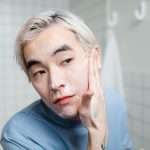 Asian man applying foaming cleanser for healthy skin care routine indoors. Un homme asiatique appliquant un nettoyant moussant pour une routine de soins de la peau saine en intérieur.