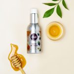 Natural honey face cleanser with honeycomb dipper and leaves on a white background. Nettoyant visage au miel naturel avec cuillère en nid d'abeille et feuilles sur fond blanc.