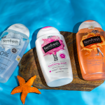 Three Femfresh intimate wash bottles alongside a starfish on a rock near a pool under sunlight. Trois bouteilles de gel intime Femfresh aux côtés d'une étoile de mer sur un rocher près d'une piscine en plein soleil.