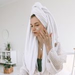 A woman in a bathrobe applies skincare indoors, enhancing her beauty routine. Une femme en peignoir applique des soins de la peau à l'intérieur, améliorant sa routine beauté.