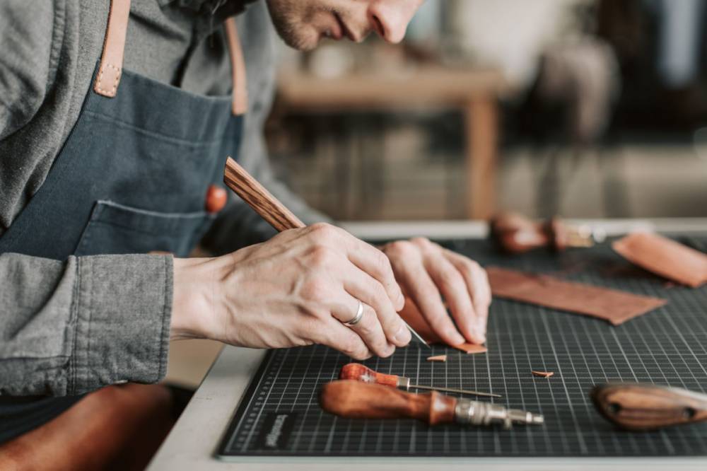 Artisan maroquinier travaillant le cuir à la main dans son atelier