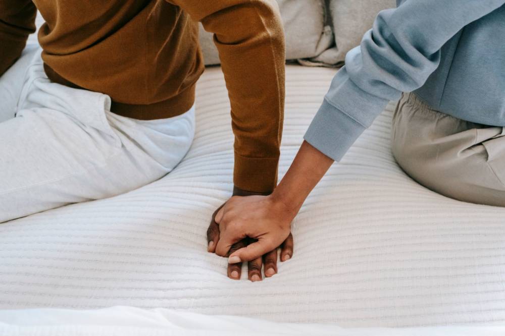 Couple assis sur un lit se tenant la main