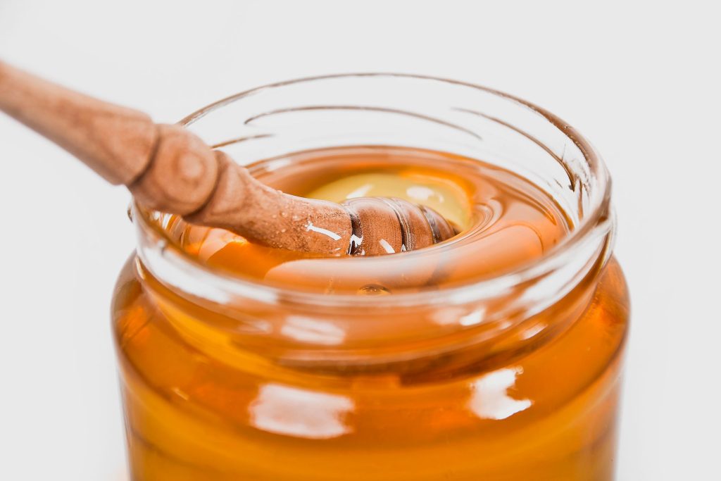 Miel doré à la cuillère en bois dans un bocal