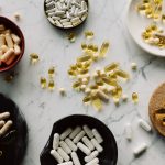Variété de gélules et de comprimés exposés dans des bols sur une table en marbre, idéal pour les concepts de santé.
