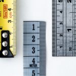 High-resolution image of a tape measure and rulers, showing precise millimeter, centimeter, and inch markings. Image haute résolution d'un mètre ruban et de règles, montrant des marquages précis en millimètres, centimètres et pouces.